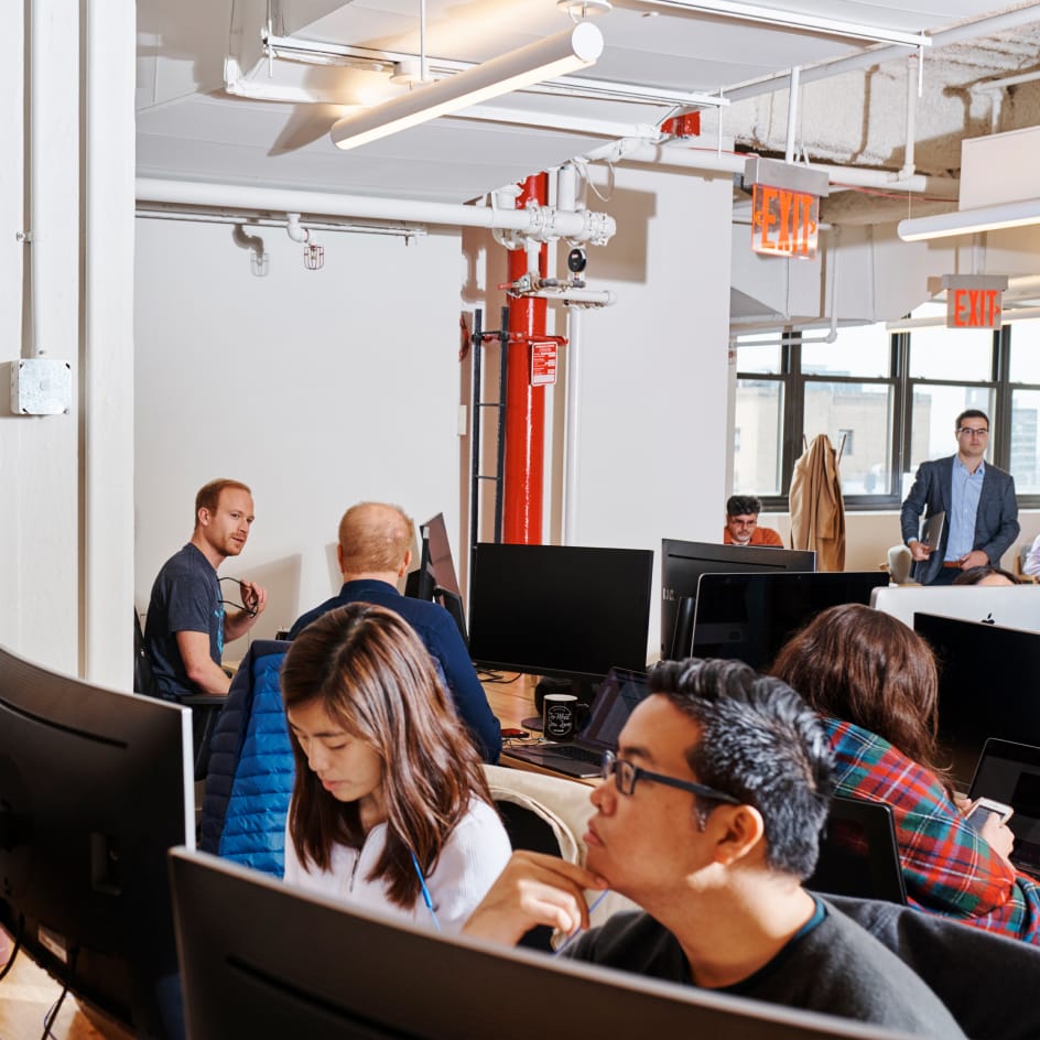 seven people scattered around an office space working